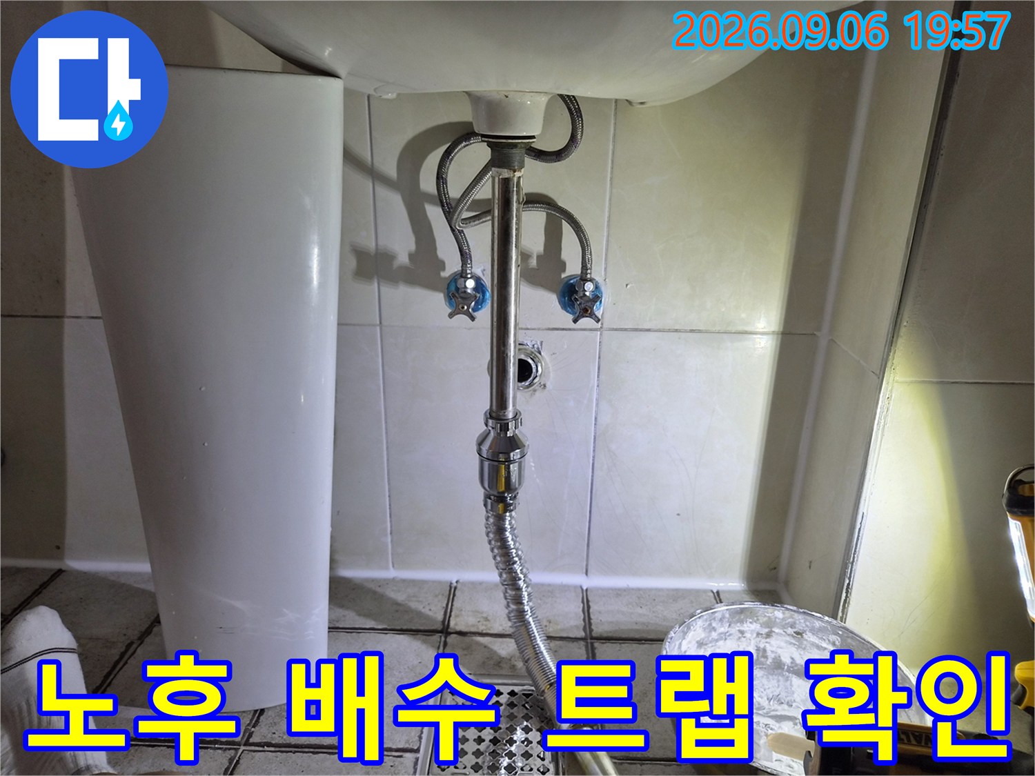 세면대 아래쪽 은색 배수 호스와 파란색 수전 밸브 상세 모습