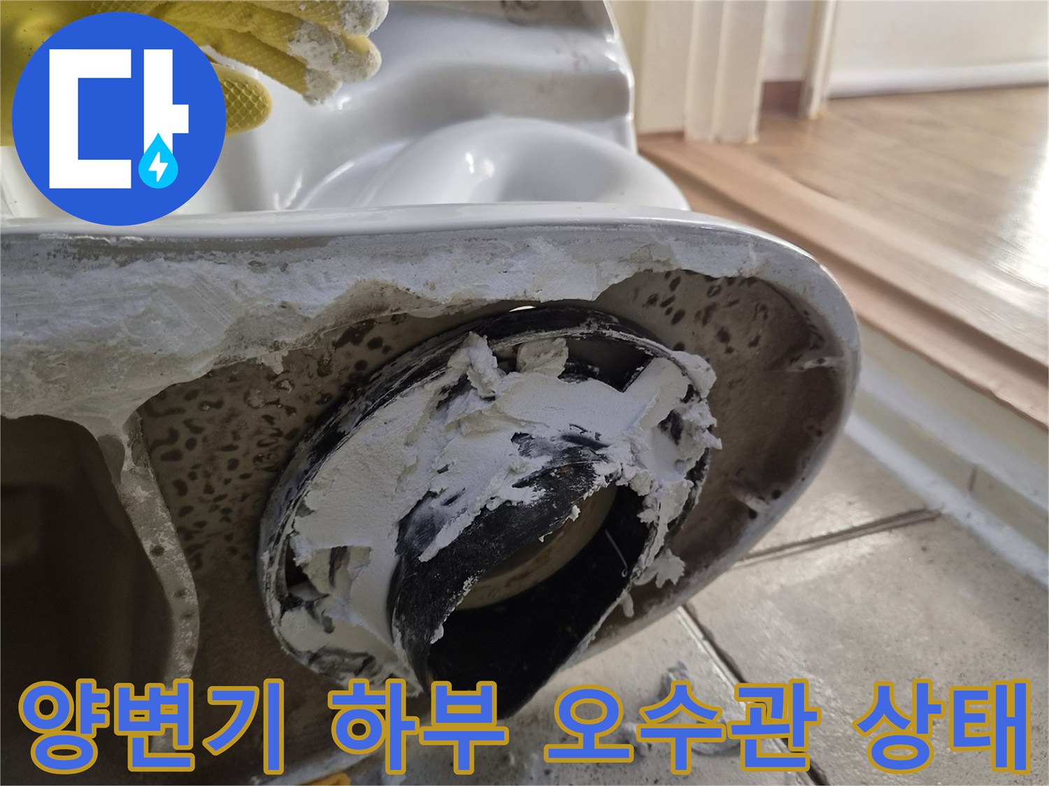 양변기를 탈거한 후 드러난 오수관 주변의 이물질과 부식된 상태를 보여주는 사진입니다.