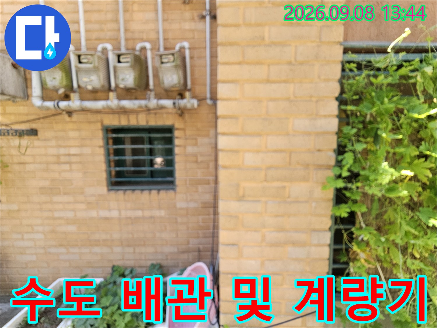 벽돌로 된 건물 외벽에 설치된 수도 계량기와 연결된 배관들입니다.