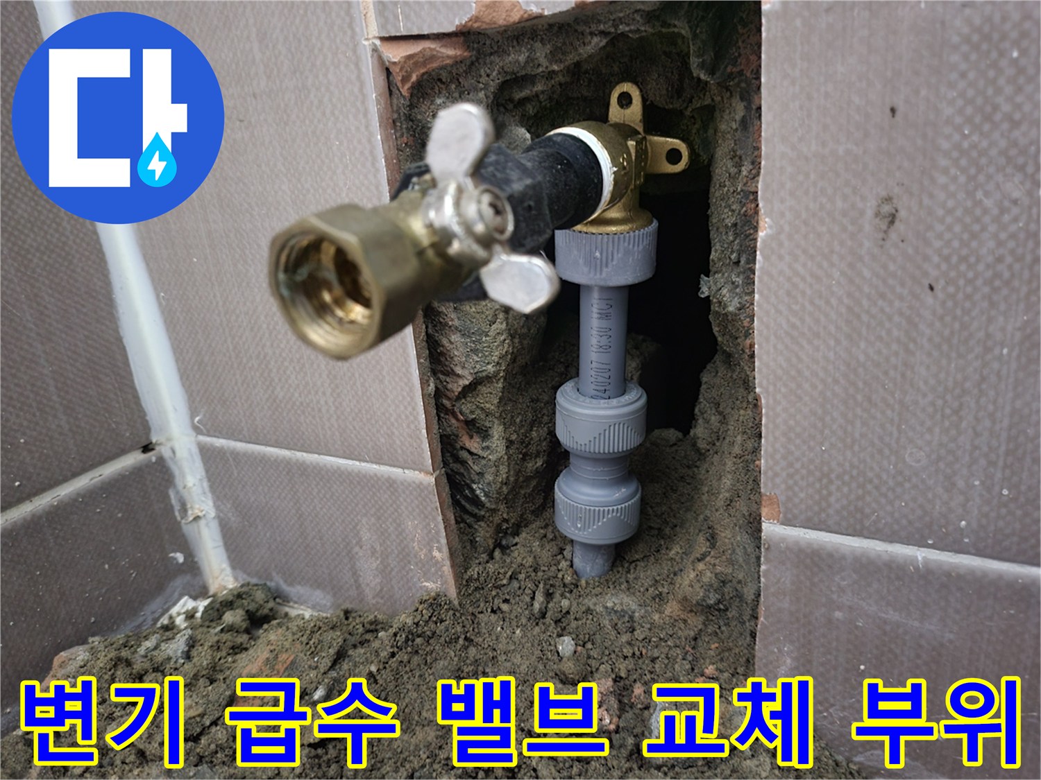 벽면 타일 파쇄 후 드러난 금색 밸브와 회색 배관 연결부