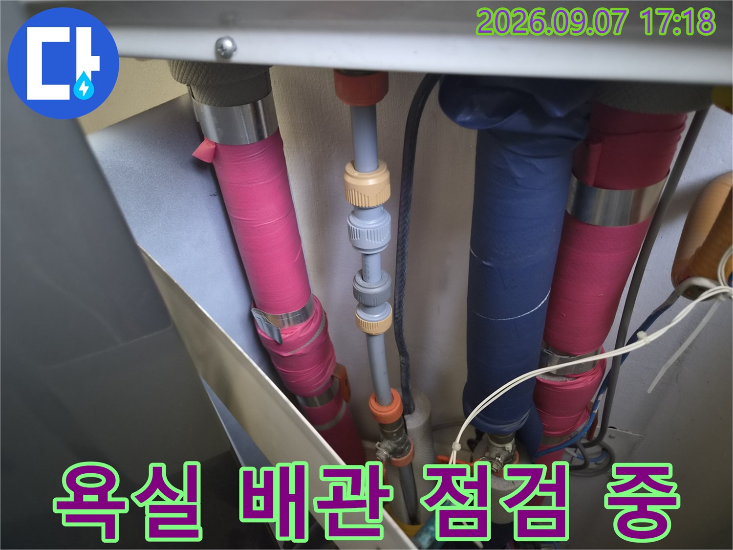 분홍색 테이프와 파란색 덮개가 입혀진 배관들의 연결 부위를 근접하여 확인하는 모습입니다.