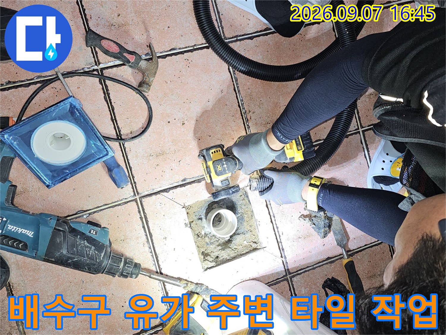 배수구 배관을 중심으로 타일을 걷어내고 공구를 사용하여 보수하는 모습