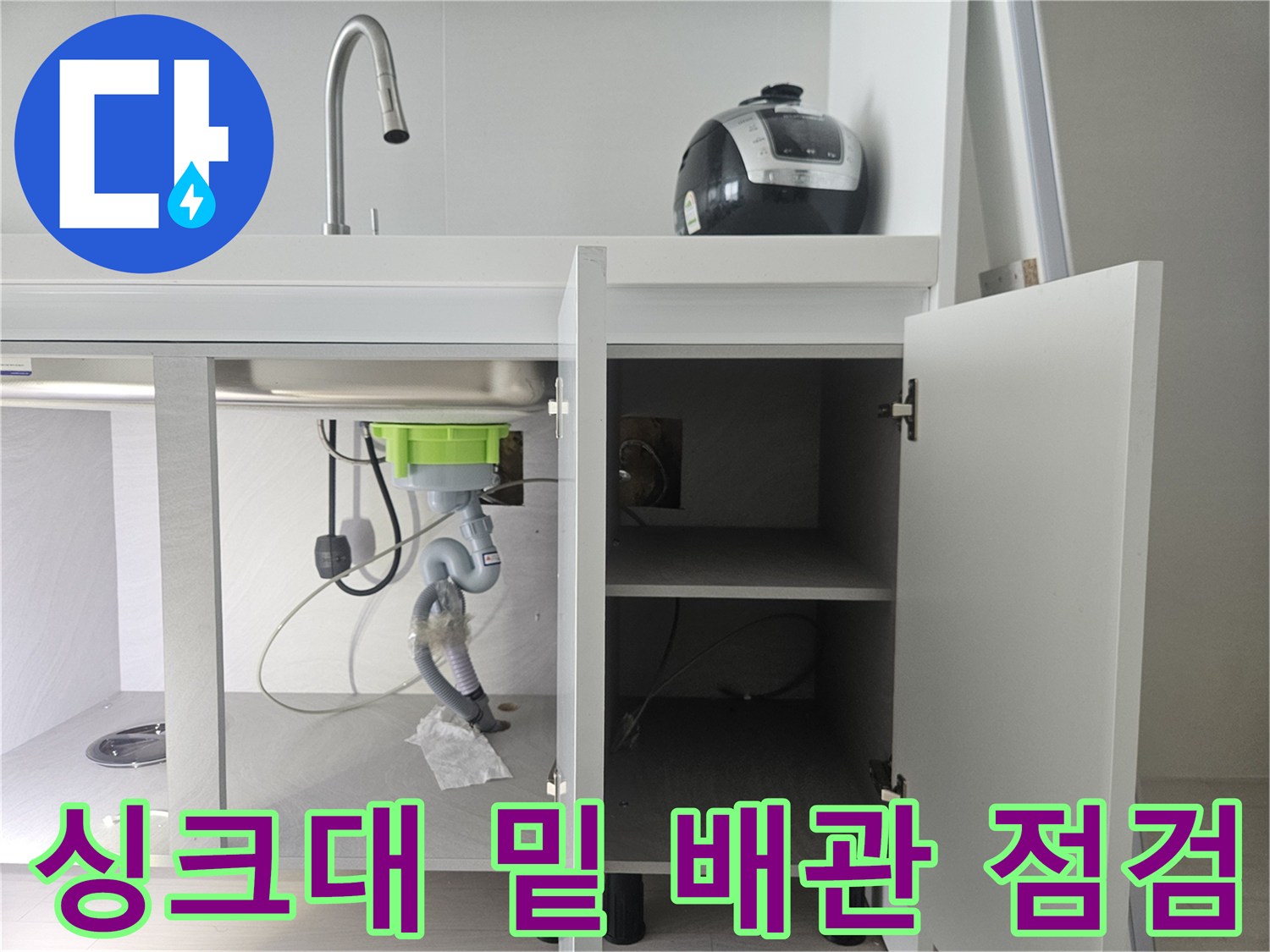 싱크대 하부장 내부의 정수기 및 배수 호스 연결 모습
