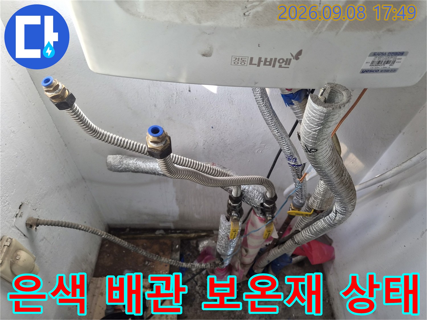 보일러 하단에 배치된 은색 보온재 배관-연결 부위 근접