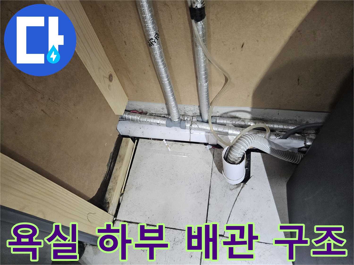 세면대 아래 은색 보온재가 감싸진 배관과 수전 연결 호스의 모습입니다.