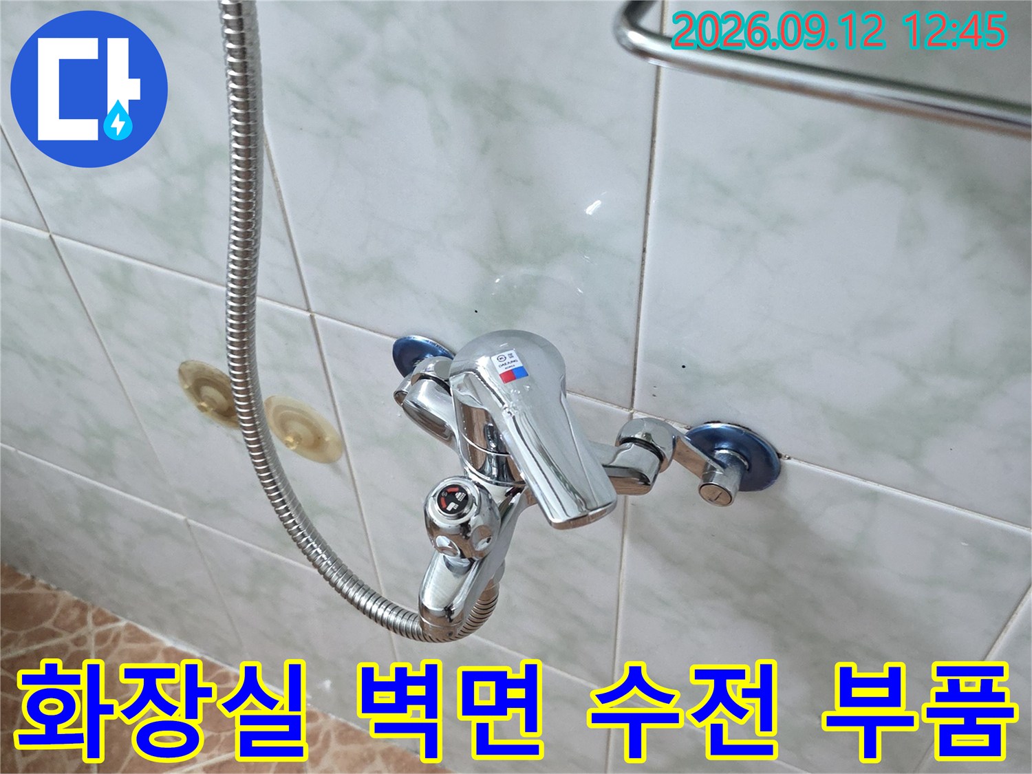 벽면에 고정된 샤워용 수전과 유연한 금속 샤워 호스 상세 사진