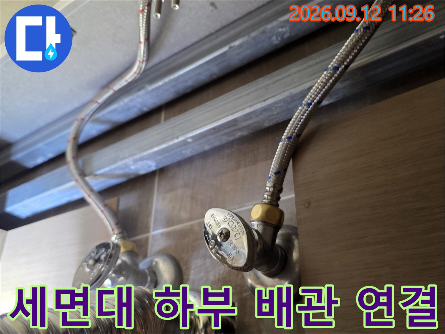 금속 재질의 앵글밸브와 은색 급수 호스가 연결된 세면대 내부 모습