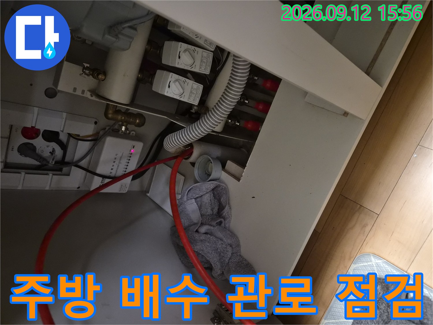 싱크대 하부장 안쪽의-급수 밸브와 배수 호스 연결 상태를 촬영한 사진입니다.
