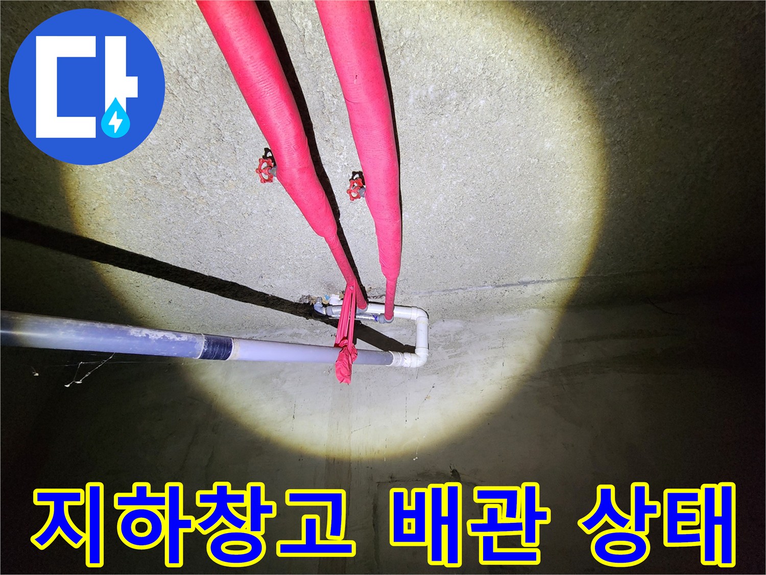 지하 창고 천장에 설치된 빨간 보온재가 감겨진 난방 배관의 모습입니다.