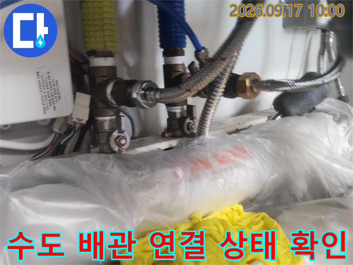 싱크대 아래 파란색과 노란색 호스가 연결된 수도 배관의 모습입니다.