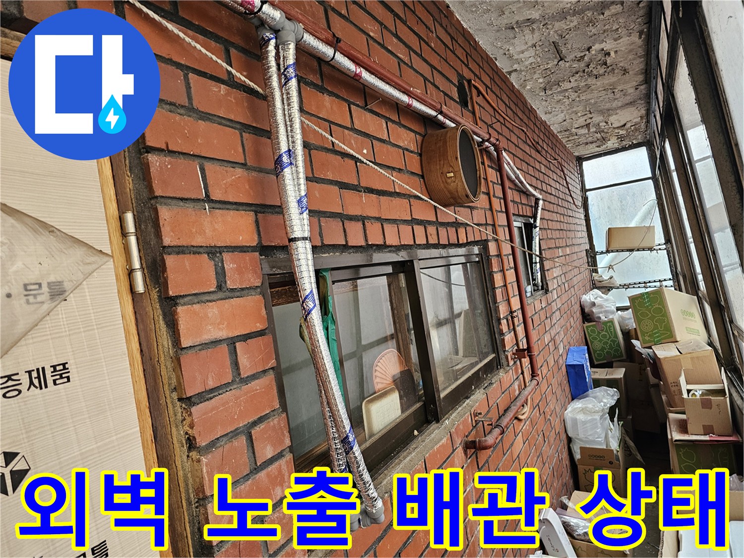 붉은 벽돌 외벽에 설치된 노출형 배관과 연결 부위 모습