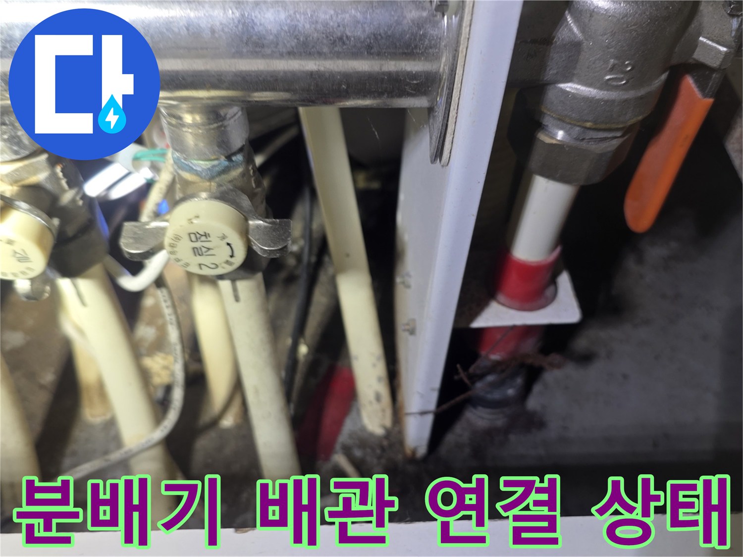 보일러 분배기의 밸브와 하얀색 배관들이 복잡하게 연결된 모습입니다.